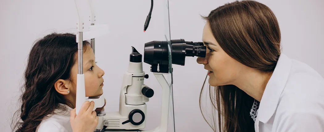 Oftalmologista examinando uma criança utilizando aparelho médico.